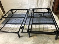 Black metal queen bed frame with wire grid base and electric motor mechanism on the right side.