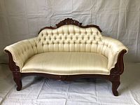 Front view of antique settee showing upholstery and carved wood frame
