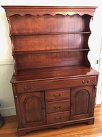 Front view of the antique style wooden hutch showing two open shelves, three central drawers, and two side cabinet doors with brass handles.