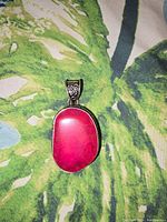 Front view of an oval pink lepidolite crystal pendant with a silver-tone bail, showing the vibrant natural texture of the stone.