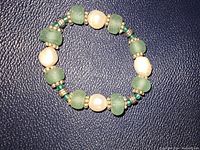 Top view of stretch bracelet showing alternating pearls and turquoise color stones with silver spacer beads on a dark textured surface.