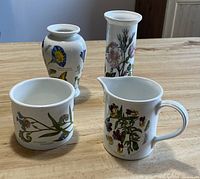 Set of four china pieces on wooden table showing front and side views.