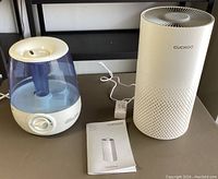 Full view of Cuckoo air purifier and Vicks humidifier side by side with power cord and user manual.