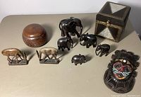 Family of carved wood items including elephants, gazelles, bowl with lid, decorative box, and tribal mask