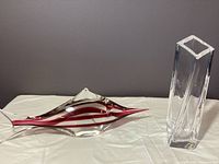 Clear view of the pink striped crystal fish by Oggetti alongside the Kosta Boda square vase on a white surface under neutral lighting