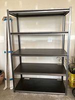 Front view of Whalen metal shelving unit with five black metal shelves and structural braces, in good condition with minimal wear.
