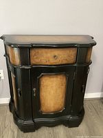 Front view of Vintage Pulaski two-tone wood composite cabinet featuring one drawer, cupboard door with keyhole, and scroll details.