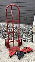 Front view of red metal hand truck with two large wheels and red wheeled movers placed in front