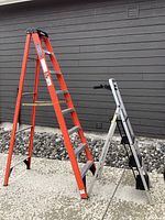 Side view of both ladders, showing the 8ft orange Werner step ladder and the smaller aluminum step stool