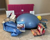 Full lot showing Bosu balance ball, hand weights, DVDs, and yoga apparel with pink/purple bag
