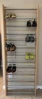 Vertical view of shoe rack with 8 horizontal metal bars holding multiple pairs of shoes