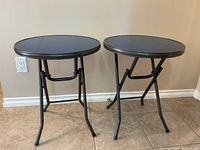 Front view of two round blue folding tables side by side on tile floor.