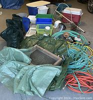 Wide shot of all items including bags, cooler, bins, fishing net, hoses, mesh netting, and sand sifter