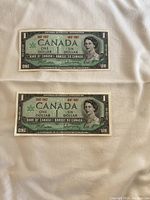 Front side of two 1967 Canadian one dollar bills, showing Queen Elizabeth II portrait and denomination.