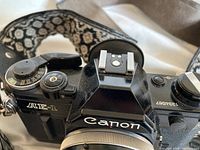 Top-down view of camera body showing AE-1 logo, Canon branding and patterned strap