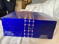 Blue Vogue Dolls box with heart-patterned grid strap, edge view