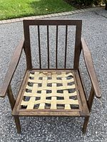 Front view of walnut chair frame showing spindle back, curved armrests and woven seat webbing