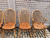 Close-up of three chairs showing the natural oak wood, spindle backs, sculpted seats and turned legs.