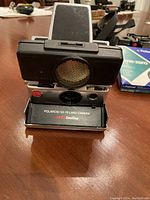 Front view of Polaroid SX-70 Land Camera with built-in sonar sensor and viewfinder flipped up