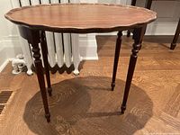 Full side view of the antique occasional table showing scalloped edge top and turned legs