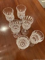 Six cut glass wine glasses arranged in a cluster viewed from above showing detailed facets and patterns.
