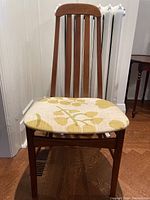 Full front view of the teak chair with upholstered floral seat pad showing form and condition.