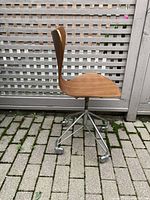Side profile of chair showing teak seat and chrome five-star caster base