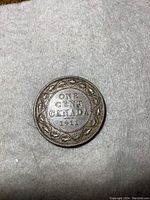 Close-up of the reverse side of the 1911 Canadian one cent large penny coin showing the denomination, country, year, and maple leaf wreath design.