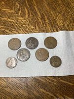 7 antique British pennies and halfpennies laid out on white paper towel, showing front face with seated Britannia design.