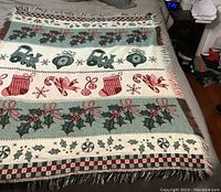 Full view of the Christmas throw blanket laid flat showing holiday-themed patterned bands with tractors, ornaments, stockings, holly, and snowflakes.