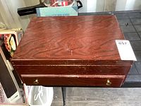 Closed view of vintage wooden cutlery chest showing reddish brown finish, rectangular shape with brass drawer pulls.