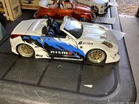 Side view of white Nismo Nissan 350Z diecast model car on black surface showing racing decals and gold wheels