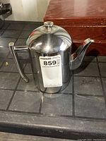 Front-side view of a polished stainless steel teapot with handle and spout, showing MaxSold tag.