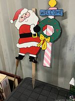 Front view of full wooden Santa yard sign with attached Welcome wreath and candy cane post.