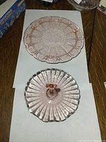 Top and side views showing large pink glass cake plate with detailed floral and geometric embossed patterns and no chips.