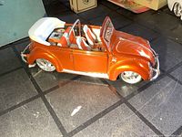 Side view of orange and white 1951 Volkswagen convertible diecast model with door open showing interior seating.
