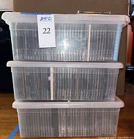 Three stacked translucent plastic storage cases filled with CDs
