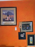 Four framed art prints displayed on orange wall