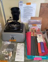 Full view of grinder base, splash hood, assorted wheels and tips in tray