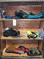 Wide view of shelving unit displaying the assorted hiking gear including hip packs, bags, small tools, lantern, wallets, and other accessories.