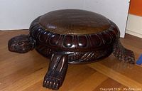 Full view of carved turtle footstool showing overall shape and cushion