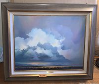 Front view of framed oil painting showing cloudscape artwork