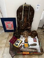 Assorted Ganesha statues, framed print, shell bead necklace, laminated card, decorative pouch, smudge bundles, incense sticks, prayer booklets and ritual items arranged on floor.