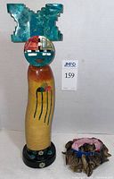 Front view of the polished stone sculpture and sheep hoof rattle on neutral background