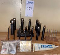 Front and top view of Pepe dapping punches mounted on labeled wooden base, with millgrain tools, micro tools in packaging, and Foredom lubricant tube in front.