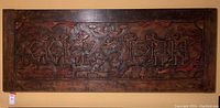 Full frontal view of entire carved wood wall panel hanging on wall