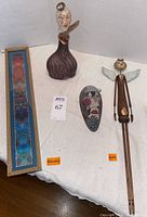 All four items displayed on a white background: framed art, two ceramic pieces, metal angel figure.