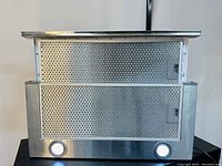 Front view of stainless steel range hood with two aluminum mesh filters and illuminated LED lights