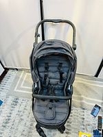 Front view of gray Baby Jogger stroller showing padded seat and safety harness straps.
