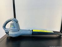 Side angle of blue Yardworks corded electric leaf blower showing full length from handle to nozzle.